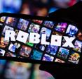 Cellphone held my hand in the dark, screen with many squares game images and the word ROBLOX across