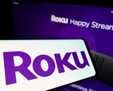 Roku purple logo on phone screen and in the back on TV 