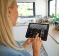 A woman at home using a smart home application on her tablet. 