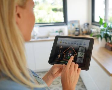 A woman at home using a smart home application on her tablet. 