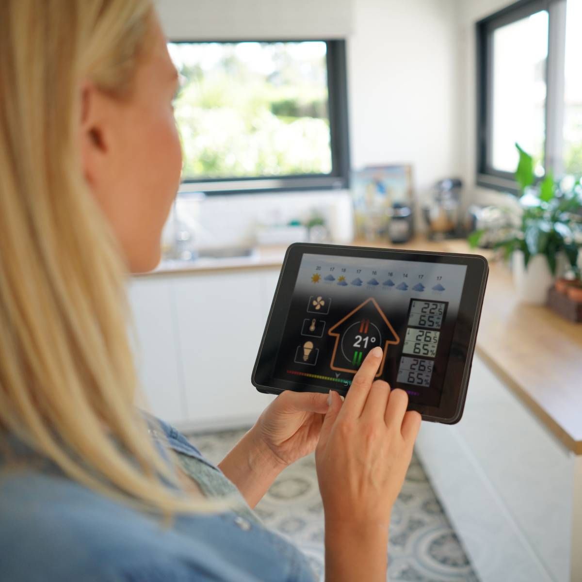 A woman at home using a smart home application on her tablet. 