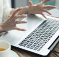 A close-up photo of a woman&#x27;s tensed hands raised above her laptop keyboard to signify a slow computer