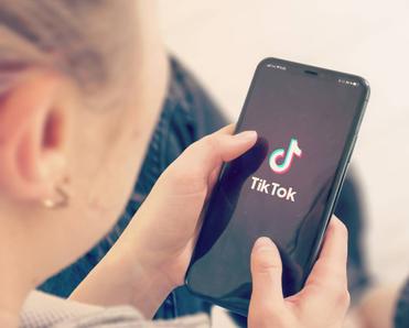 A young girl opening TikTok on her smartphone.