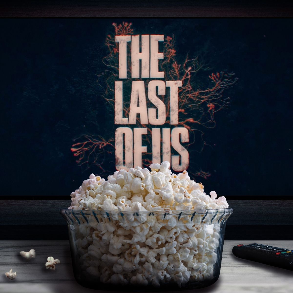 Tv in the background with The Last of Us on the screen and in front a bowl of popcorn and a remote control