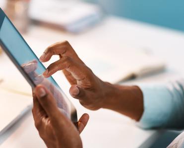 A close-up of a man&#x27;s hands holding a tablet and tapping the screen