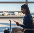 A woman uses her cell phone on public Wi-Fi while waiting to board a flight at the airport.