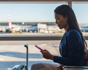 A woman uses her cell phone on public Wi-Fi while waiting to board a flight at the airport.