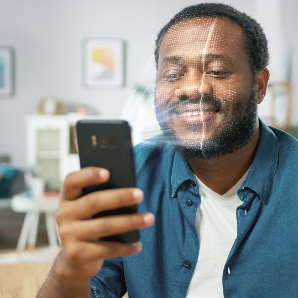 A young bearded Black man holds his cell phone in front of his face with an illustration of the phone&#x27;s camera scanning his face so he can log into his phone using facial recognition