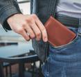 A man pulls a brown leather wallet out of his pocket. Some people claim RFID wallets are necessary to prevent RFID fraud, but is that really true?