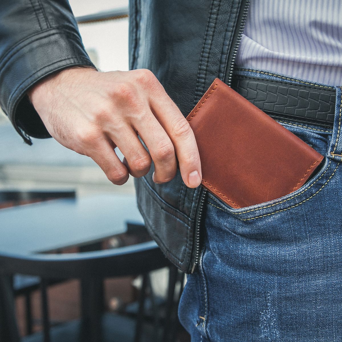 A man pulls a brown leather wallet out of his pocket. Some people claim RFID wallets are necessary to prevent RFID fraud, but is that really true?