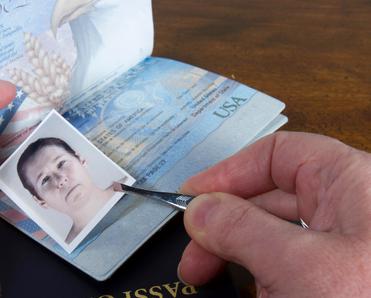 A close-up of a man&#x27;s hands fording a US passport, which can be a type of synthetic identity theft.