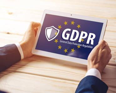 Two hands are holding a tablet with a screen on the GDPR and the EU flag in the background.